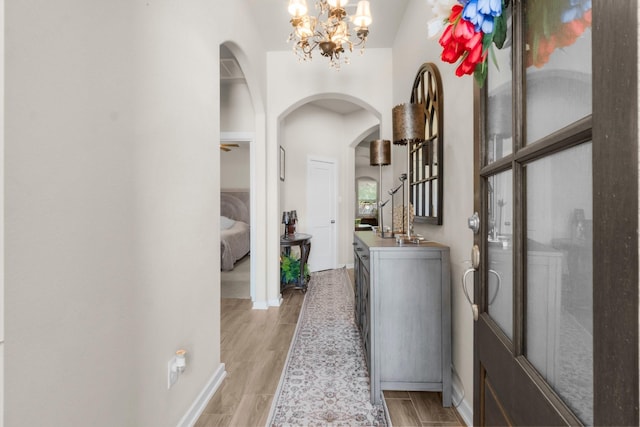 371 Westlake Terrace Dr, Conroe, TX 77304 - corridor featuring arched walkways, a chandelier, light wood-type flooring, and baseboards