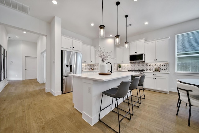 296 N Cascade Heights Dr, Montgomery, TX 77316 - kitchen featuring appliances with stainless steel finishes, tasteful backsplash, a breakfast bar, light wood-style flooring, and recessed lighting