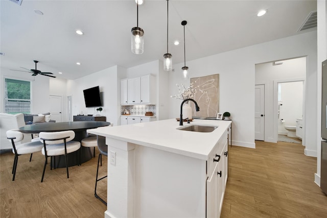 296 N Cascade Heights Dr, Montgomery, TX 77316 - kitchen featuring a sink, light wood-type flooring, an island with sink, white cabinets, and backsplash