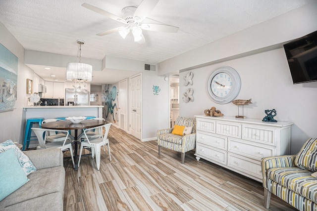 7310 Seawall Blvd Unit 210, Galveston, TX 77551 - living area featuring a chandelier, light wood-type flooring, a ceiling fan, a textured ceiling, and baseboards
