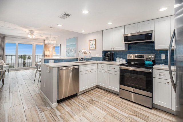 7310 Seawall Blvd Unit 210, Galveston, TX 77551 - kitchen featuring stainless steel appliances, a sink, a peninsula, light countertops, and white cabinets