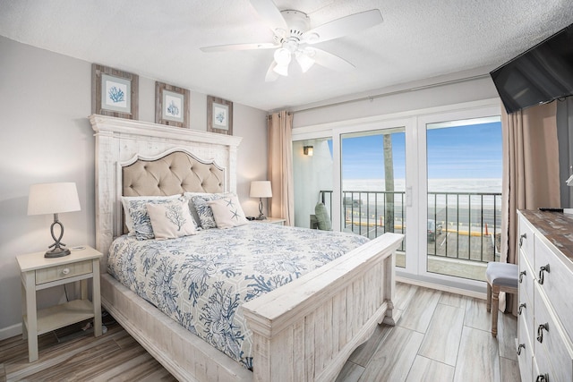 7310 Seawall Blvd Unit 210, Galveston, TX 77551 - bedroom featuring access to outside, ceiling fan, a textured ceiling, light wood-style flooring, and baseboards