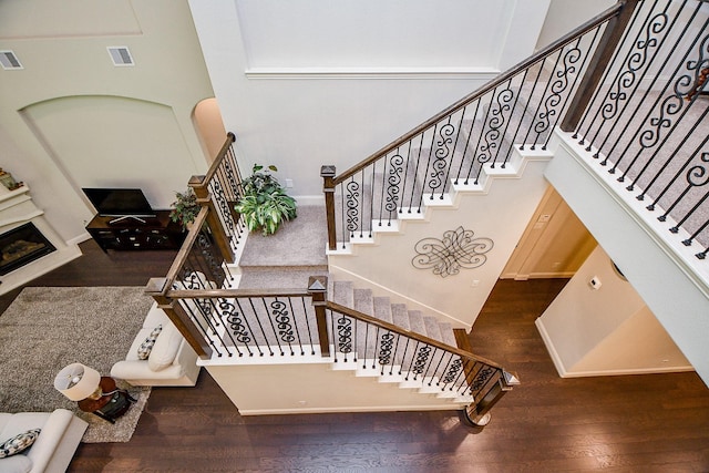 1704 Graystone Hills Dr, Conroe, TX 77304 - stairway with wood finished floors, a towering ceiling, a fireplace, and baseboards