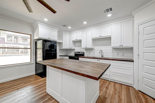6121 County Road 225, Hungerford, TX 77448 - kitchen featuring butcher block counters, stainless steel range with electric cooktop, freestanding refrigerator, a sink, and white cabinets