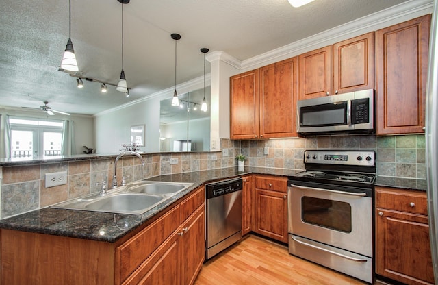 1711 Old Spanish Trl Unit 401, Houston, TX 77054 - kitchen with stainless steel appliances, a sink, ornamental molding, brown cabinets, and a peninsula