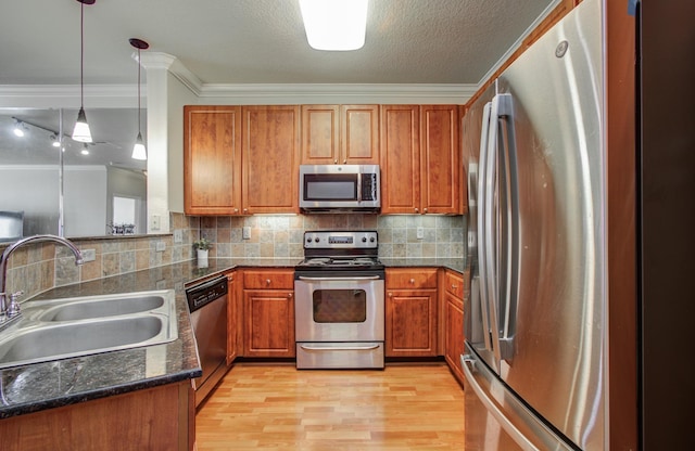 1711 Old Spanish Trl Unit 401, Houston, TX 77054 - kitchen with appliances with stainless steel finishes, a sink, brown cabinetry, crown molding, and light wood-type flooring