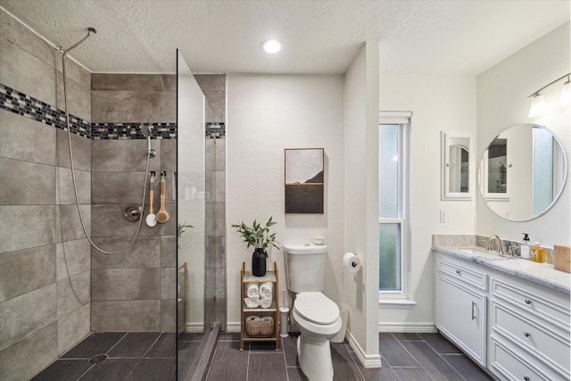 2227 Holly Knoll St, Houston, TX 77077 - bathroom with vanity, a tile shower, toilet, a textured ceiling, and baseboards