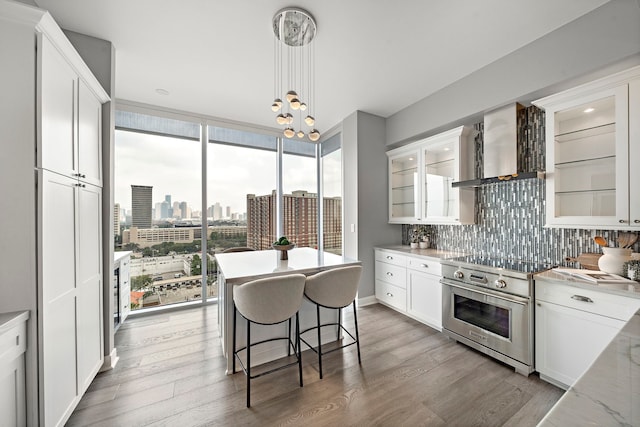 3333 Allen Pkwy Unit 1302, Houston, TX 77019 - kitchen featuring premium range, wall chimney range hood, backsplash, white cabinetry, and expansive windows