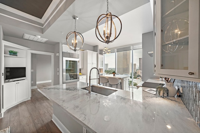 3333 Allen Pkwy Unit 1302, Houston, TX 77019 - kitchen with a sink, a chandelier, wood finished floors, wine cooler, and light stone counters