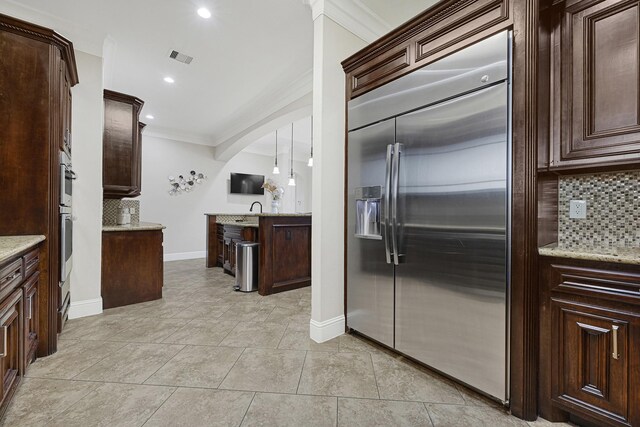 13635 Reeveston Rd, Houston, TX 77039 - kitchen with built in refrigerator, decorative backsplash, crown molding, arched walkways, and baseboards