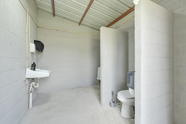 13635 Reeveston Rd, Houston, TX 77039 - bathroom featuring concrete floors, toilet, concrete block wall, and lofted ceiling