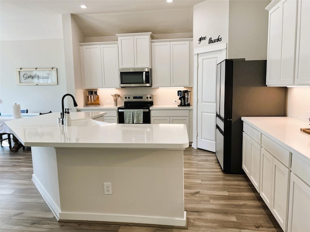 11755 Oakwood Ranch Dr, Willis, TX 77378 - kitchen featuring stainless steel microwave, electric range, recessed lighting, an island with sink, and white cabinetry
