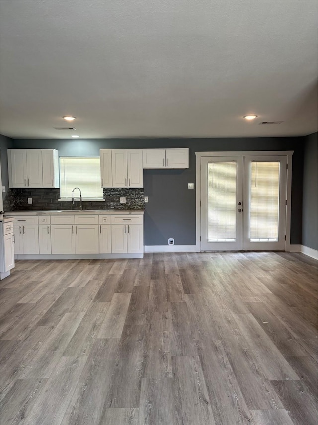 5159 Dumore Dr, Houston, TX 77048 - kitchen with tasteful backsplash, light wood finished floors, baseboards, french doors, and white cabinetry