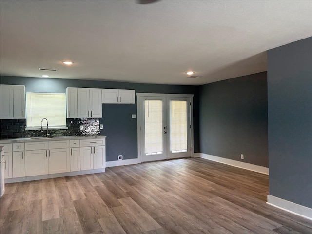 5159 Dumore Dr, Houston, TX 77048 - kitchen with a sink, tasteful backsplash, baseboards, white cabinets, and light wood-style flooring