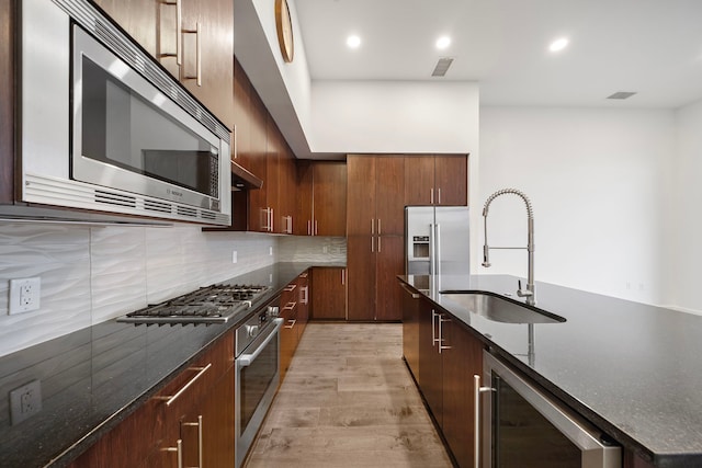 4820 Caroline St Unit 507, Houston, TX 77004 - kitchen featuring stainless steel appliances, a sink, beverage cooler, light wood-type flooring, and backsplash