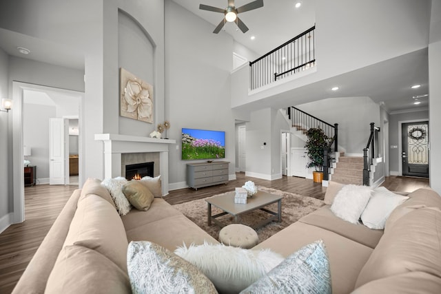 2310 Desert Holly Dr, Katy, TX 77493 - living area featuring stairway, a ceiling fan, a fireplace, wood finished floors, and a towering ceiling