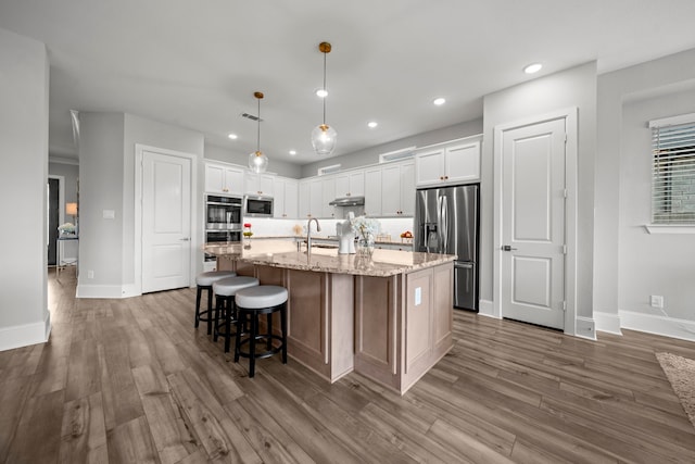 2310 Desert Holly Dr, Katy, TX 77493 - kitchen with appliances with stainless steel finishes, wood finished floors, recessed lighting, white cabinets, and a sink
