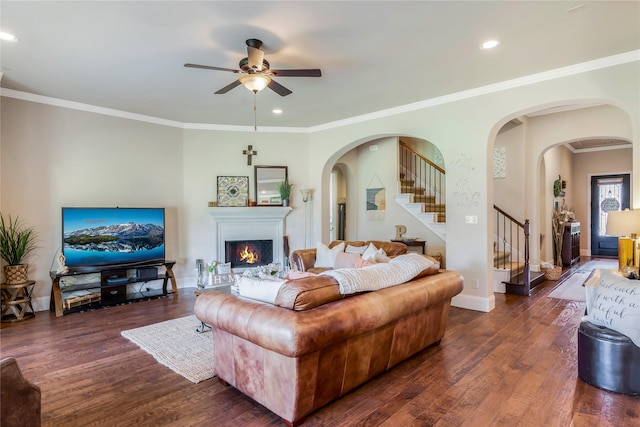 10040 Easton Sky Ln, Cypress, TX 77433 - living room featuring a ceiling fan, stairs, arched walkways, wood finished floors, and a warm lit fireplace
