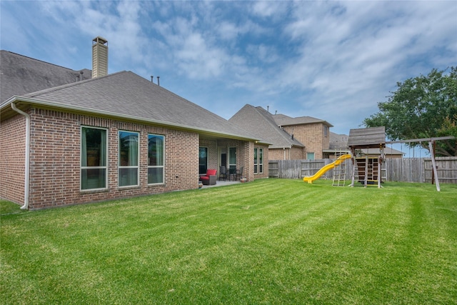 10040 Easton Sky Ln, Cypress, TX 77433 - rear view of property featuring a playground, brick siding, a chimney, a shingled roof, and a patio area