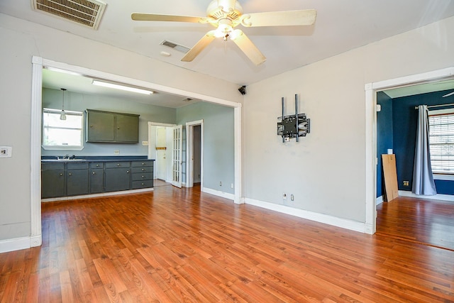 101 Emerald Ct, Houston, TX 77009 - unfurnished living room featuring ceiling fan, wood finished floors, baseboards, and a sink