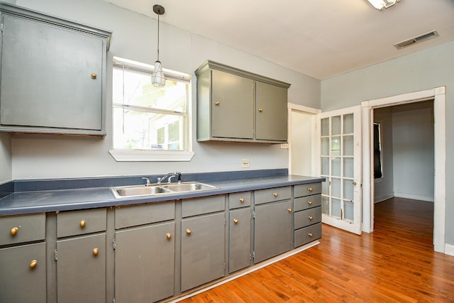 101 Emerald Ct, Houston, TX 77009 - kitchen with gray cabinets, a sink, dark countertops, and light wood-type flooring