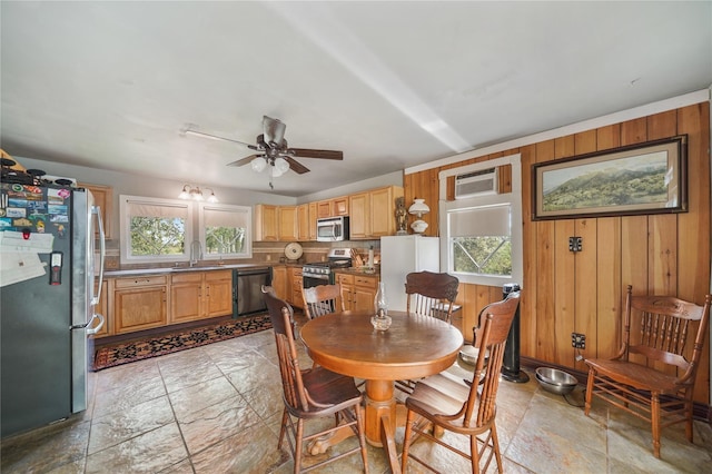 855 County Road 15, Damon, TX 77430 - dining space with wooden walls, a ceiling fan, light stone finish floors, and a wall mounted air conditioner