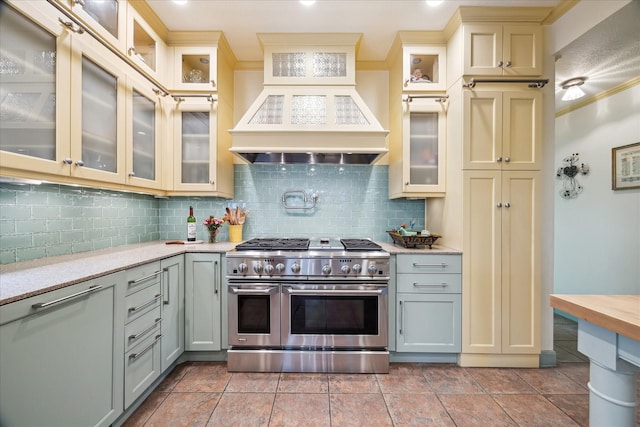 210 Victoria Way, Friendswood, TX 77546 - kitchen with range with two ovens, cream cabinetry, ornamental molding, decorative backsplash, and premium range hood