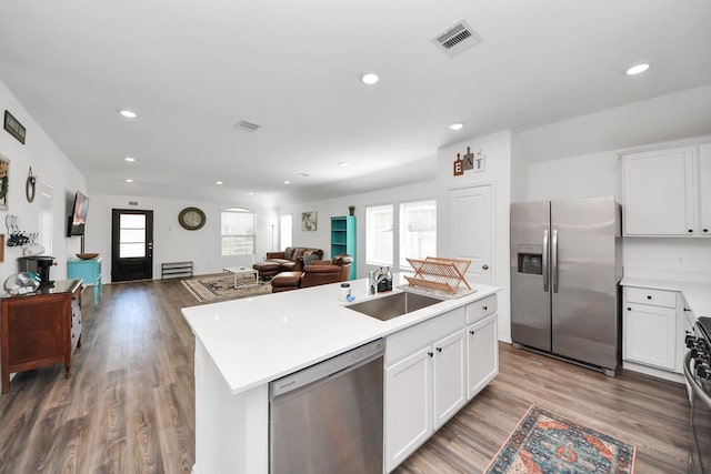 2947 Palominos Way, Conroe, TX 77301 - kitchen with stainless steel appliances, a sink, a kitchen island, open floor plan, and light wood-style flooring