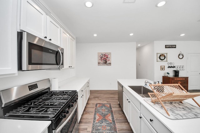 2947 Palominos Way, Conroe, TX 77301 - kitchen with appliances with stainless steel finishes, a sink, wood finished floors, recessed lighting, and white cabinets