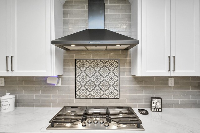 7519 Foster Creek Dr, Richmond, TX 77406 - kitchen with wall chimney exhaust hood, stainless steel gas cooktop, white cabinets, light stone countertops, and backsplash