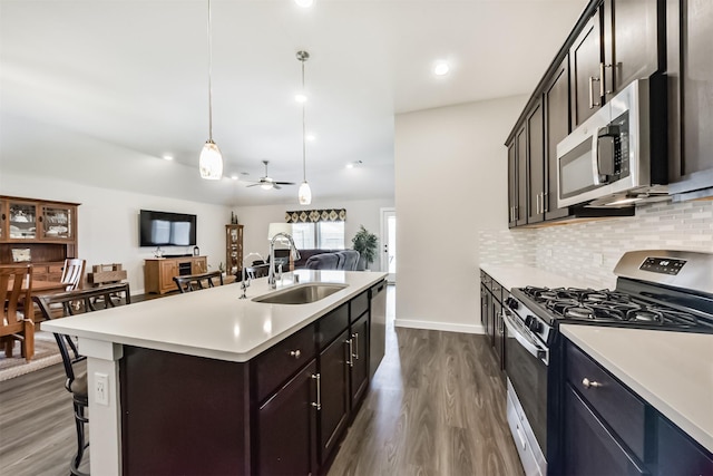 22107 Juniper Crossing Dr, New Caney, TX 77357 - kitchen featuring appliances with stainless steel finishes, a sink, dark wood finished floors, decorative backsplash, and light countertops