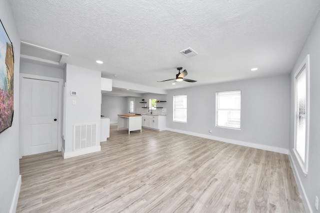 503 Schilling St, Baytown, TX 77520 - unfurnished living room with a textured ceiling, light wood-type flooring, baseboards, ceiling fan, and recessed lighting