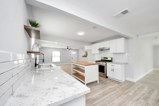 503 Schilling St, Baytown, TX 77520 - kitchen featuring gas range, a sink, under cabinet range hood, open shelves, and baseboards
