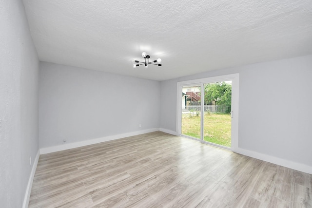 503 Schilling St, Baytown, TX 77520 - empty room featuring a chandelier, light wood-style flooring, baseboards, and a textured ceiling
