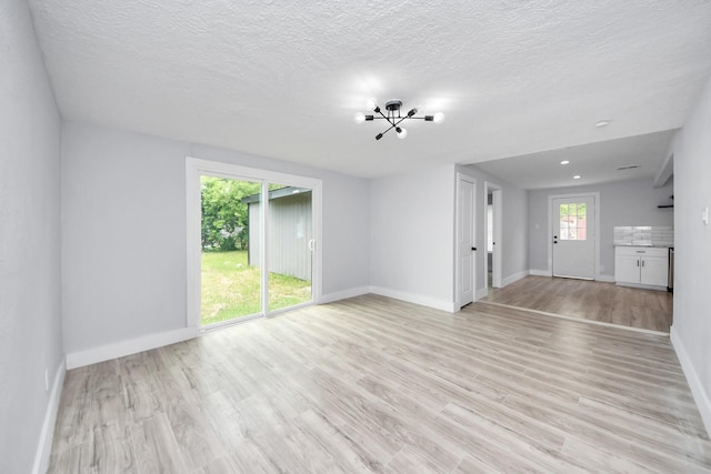 503 Schilling St, Baytown, TX 77520 - unfurnished living room with light wood-type flooring, baseboards, and a textured ceiling