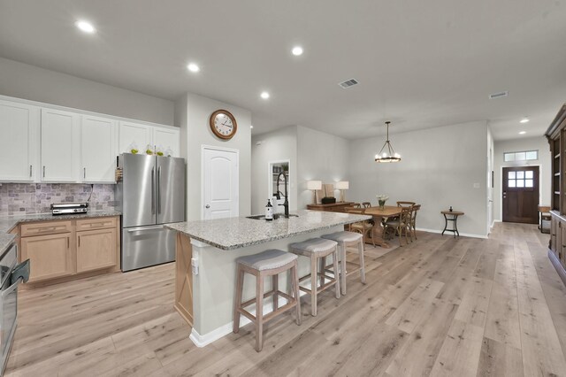 9203 White Tail Dr, Conroe, TX 77303 - kitchen with freestanding refrigerator, light wood finished floors, light stone counters, backsplash, and recessed lighting