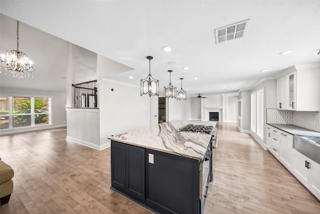 17511 Cassina Dr, Spring, TX 77388 - kitchen with open floor plan, a chandelier, recessed lighting, white cabinets, and light stone counters