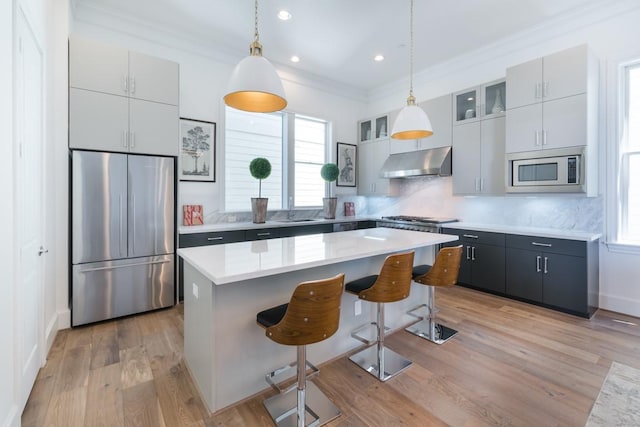 2209 Crocker St, Houston, TX 77006 - kitchen with built in appliances, under cabinet range hood, ornamental molding, a kitchen bar, and decorative backsplash