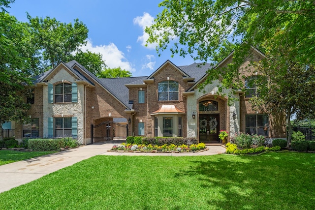 72 Tall Trl, Missouri City, TX 77459 - traditional home featuring a front lawn, brick siding, stone siding, and a gate