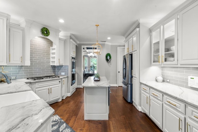 72 Tall Trl, Missouri City, TX 77459 - kitchen featuring appliances with stainless steel finishes, white cabinetry, a center island, backsplash, and crown molding
