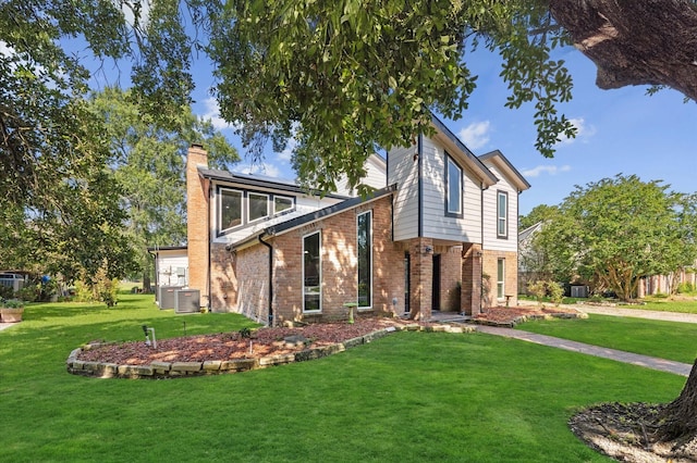20407 Spoonwood Dr, Humble, TX 77346 - view of front of property featuring brick siding, a chimney, roof mounted solar panels, and a front lawn