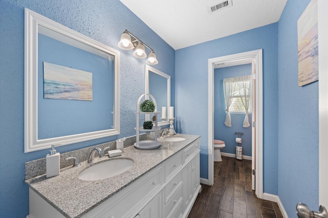 20407 Spoonwood Dr, Humble, TX 77346 - full bathroom with toilet, double vanity, wood finished floors, and baseboards