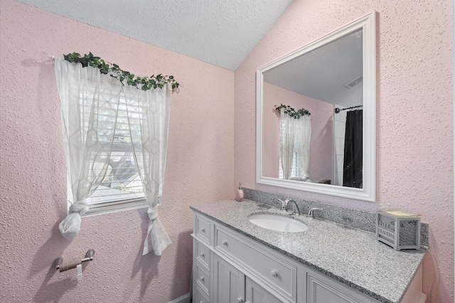 20407 Spoonwood Dr, Humble, TX 77346 - bathroom with vanity, a textured wall, a textured ceiling, and vaulted ceiling