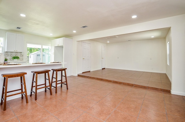 14934 Arundel Dr, Channelview, TX 77530 - kitchen featuring recessed lighting, light tile patterned floors, a breakfast bar area, white cabinetry, and light countertops