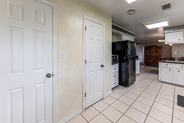 13477 Fm 977 W, Marquez, TX 77865 - kitchen featuring freestanding refrigerator, white cabinets, stainless steel microwave, and light tile patterned flooring