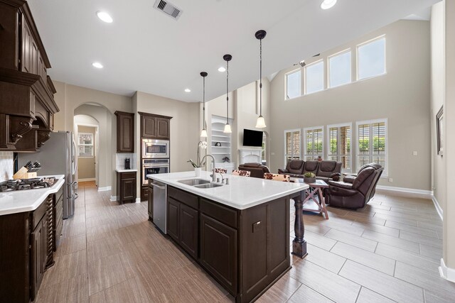 2506 Haven Hill Dr, Katy, TX 77494 - kitchen featuring a sink, arched walkways, appliances with stainless steel finishes, dark brown cabinets, and open floor plan
