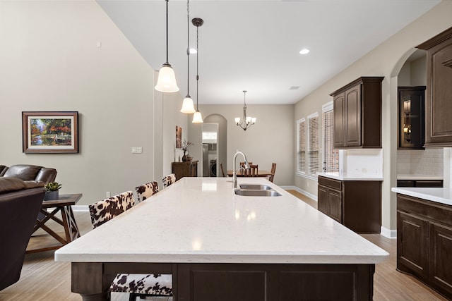2506 Haven Hill Dr, Katy, TX 77494 - kitchen with a sink, dark brown cabinets, tasteful backsplash, a center island with sink, and light wood-style floors