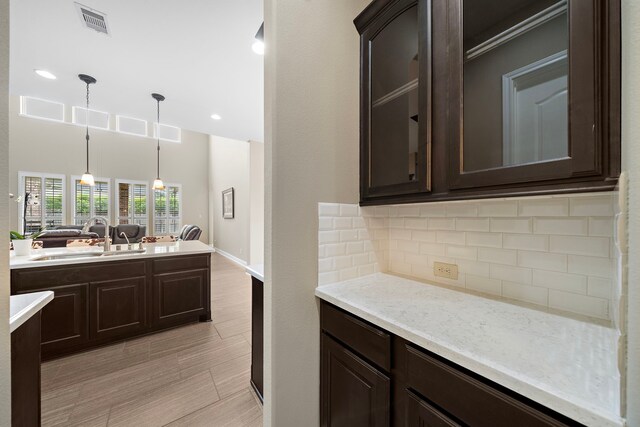 2506 Haven Hill Dr, Katy, TX 77494 - kitchen featuring a sink, dark brown cabinets, tasteful backsplash, pendant lighting, and light wood finished floors