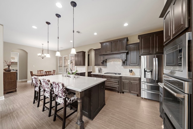 2506 Haven Hill Dr, Katy, TX 77494 - kitchen featuring appliances with stainless steel finishes, arched walkways, dark brown cabinetry, light countertops, and recessed lighting