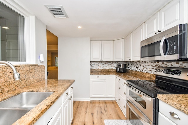 1908 Augusta Dr Unit 10, Houston, TX 77057 - kitchen with appliances with stainless steel finishes, a sink, light wood-style flooring, white cabinetry, and decorative backsplash
